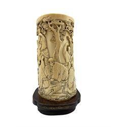 19th century Japanese ivory tusk vase finely carved with a continuous scene of figures gathered outside around a storyteller beneath pine trees and clouds, on hardwood base with gilt decoration H17cm x W10.5cm (excluding base) H20cm overall 