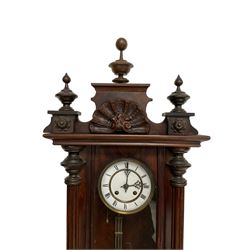 Late 19th century German 8-day striking wall clock in a mahogany case -  pediment with carved decoration and turned finials, fully glazed door flanked by carved pilasters displaying a gridiron pendulum and beat plate, two part enamel dial with gothic pierced hands and spun brass bezel, 
movement striking the hours and half hours on a coiled gong.