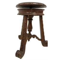 Late 19th century carved hardwood music stool, revolving adjustable seat with carved foliate and tulip decoration, splayed supports with scroll feet