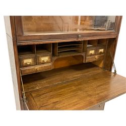 Gunn Furniture Co. - early 20th century oak barrister's or library sectional stacking bookcase, fitted with three shelves with glazed up-and-over doors, central fall-front with applied moulding foliate decoration concealing fitted interior with pigeonholes, four drawers to base