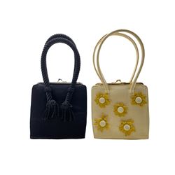 Two Anya Hindmarch handbags, the first in black with rope twist handles and the other in cream with applied felt flowers and gold coloured hardware (2)