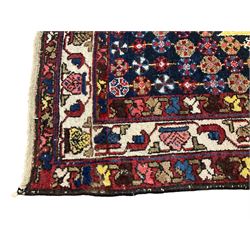 Persian Hamadan red ground rug, the field with a central lozenge medallion surrounded by stylised flower heads, the guarded ivory border decorated with repeating plant motifs