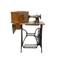 Oak cased Singer sewing table with sewing machine, raised on a cast iron base
