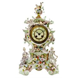 Mid-19th century continental porcelain mantle clock in the Meissen Rococo style decorated with encrusted flowers throughout and reclining figures depicting two lovers encouraged by Cupid, French twin barrel eight-day countwheel movement striking the hours and half hours on a bell, two-piece white enamel dial with upright Arabic numerals and minute markers, fleur de lis steel hands enclosed within a cast brass bezel with a flat bevelled glass. No pendulum or key