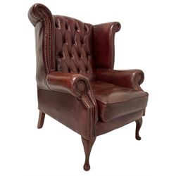 Wingback armchair, upholstered in ox blood leather, raised on cabriole supports 