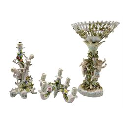 19th century Sitzendorf porcelain centrepiece modelled as three Cherubs against a floral encrusted tree supporting a pierced inverted conical basket, H42cm together with a similar style 19th century porcelain candelabra (a/f)