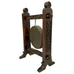 Late 19th century carved oak frame gong on stand, the pegged frame carved with scrolling foliage and flower heads, tooled bronze hanging gong, the lower pegged rail dated '1880', on splayed feet