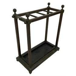 Brass stick stand, with three divisions over drop in drip tray, raised on bracket supports 