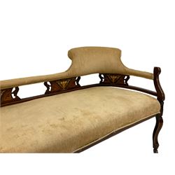 Edwardian inlaid walnut framed chaise longue, sloped back, the padded backrail carved and pierced with foliate decoration, upholstered in champagne fabric with sprung seat, raised on cabriole supports with castors