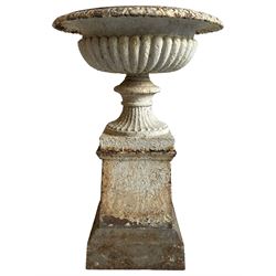 Victorian cast iron garden urn on stand, egg and dart moulded rim over gadrooned underbelly, moulded footed base, on tapered square plinth
