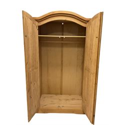Traditional pine wardrobe, the arched top over two panelled doors enclosing interior fitted for hanging and with shelf, raised on a skirted base W102cm, H190cm, D57cm