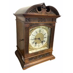 Late 19th century striking mantle clock in architectural walnut case, arched pediment with central leaf carved motif, enclosed by a bevel glazed door, fluted and lunette carved, moulded base, brass dial decorated with floral scroll mounts, silvered Roman and Arabic chapter ring, anchor escapement with twin going barrel 'Lenzkirch' movement stamped 'AUG 1 million, 358398', striking the hours and half  hours on a coiled gong, with pendulum and key, H33cm, W22cm.
