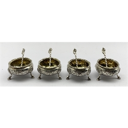 Set of four Victorian silver circular salts with embossed decoration, gilded interiors and shaped supports  with four original spoons with gilded bowls and figure finials London 1870 Maker Richards and Brown 5oz