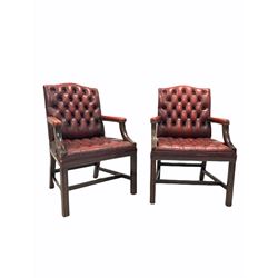 Pair of George III style library open armchairs, mahogany framed and upholstered in deep buttoned ox blood leather, raised on square moulded supports united by stretcher W66cm