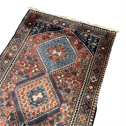 Persian Yalameh terracotta ground runner rug, the field decorated with a column of intricate geometric lozenges with interior star and hook motifs, the surrounded busy field filled with stylised floral patterns and flower heads, the guard band with further repeating lozenges