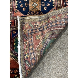Large Persian Karajeh red ground runner, eight lozenges in green blue and red, decorated with geometric patterns on a red field, guarded boarder with repeated floral and geometric motif, 430cm x 112cm