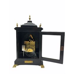 Early 20th century eight-day ebonised German bracket clock with a two train striking movement, striking the hours and quarters on two coiled gongs, ebonised case on a concave moulded plinth raised on brass bracket feet with inverted bell top and brass finials, full length glazed door with brass slip and recessed brass spandrels to the break arch, brass dial with cherub head spandrels, silvered pendulum regulation disc and scroll spandrels to the arch, 6-1/2
