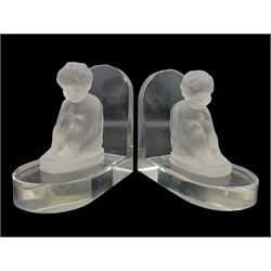 After Heinrich Hoffmann, pair of clear glass bookends each surmounted with a figure of a seated child, impressed butterfly mark, H11.5cm x W11.5cm 