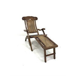 Early 20th century teak folding steamer chair, leaf scroll carved cresting rail, cane back and foot panel, and leather upholstered seat, W60cm