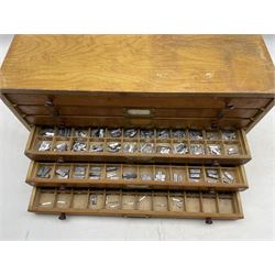 A six drawer printers chest containing a quantity of metal stamps/ matrices and other accessories, H25cm, W50.5cm, D25.5cm