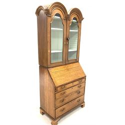 Georgian oak bureau bookcase, the associated domed top section with two arched glazed doors enclosing two adjustable shelves, over fall front revealing fitted interior, over four long graduating drawers, raised on bracket supports 
