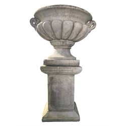 Large stone urn on plinth, the cavetto edge over gadrooned body with twin handles