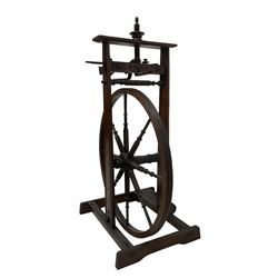 Late 19th century stained beech spinning wheel, carved decoration to the shaped frieze, the wheel with eight bobbin-turned spokes attached to a ring turned arbor with steel pivots