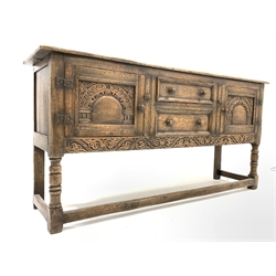 18th century style oak dresser base, with fitted drawer and another drawer flanked by two fielded cupboards, floral scroll carved apron, all raised by turned and block supports united by stretchers, 