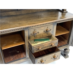 Early 20th century medium oak sideboard, raised back with floral carved frieze, two cupboards under each enclosing fixed shelf, flanking three drawers, raised on baluster turned front supports, 