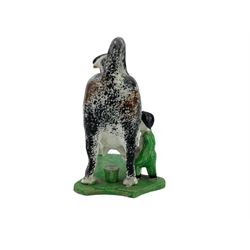 Early 19th century creamware cow creamer, probably Yorkshire, with curled tail handle, a milkmaid seated to one side with pail, decorated with sponged black and brown and set concave base, painted in green, L17cm x H15cm