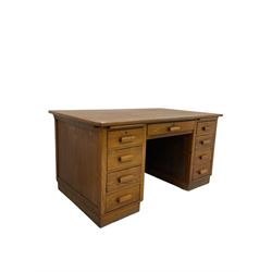 Mid-20th century oak twin pedestal desk, the flat top over one long and eight short drawers, raised on a plinth base