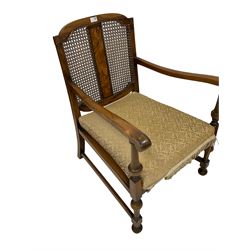 Early to mid-20th century simulated walnut open armchair with cane back, upholstered drop-in seat with fringing, raised on turned supports (60cm x 76cm x 86cm); Early to mid-20th century simulated walnut open armchair with cane back, tapered and shaped arm supports, upholstered drop-in seat (62cm x 65cm x89cm) (2)