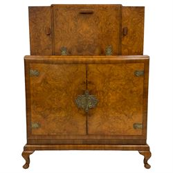 G & F Gold Feather Products Ltd. Leeds - early to mid-20th century figured walnut cocktail cabinet, double hinged central section revealing mirrored interior, two single flanking cupboards with glass shelves, double cupboard below fitted with bottle holders and shelf, mounted with ornate pierced gilt metal hinges, escutcheon plate and handles, on cabriole feet, with ivorine label to the interior