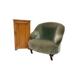 Victorian bedroom tub chair, upholstered in green velvet, raised on turned front supports and castors, together with an early 20th century ash bedside cupboard with single panelled door 
