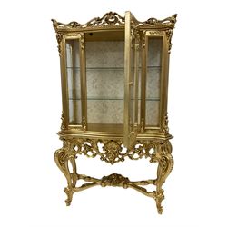 Silik Lo Stile Di Classe - Italian Rococo style carved gilt display cabinet, pierced scrolling pediment with central cartouche, fitted with single glazed door, ornate carved apron with pierced foliate and scrolled moulding, shell and flower head motifs, raised on cabriole supports united by cross stretcher