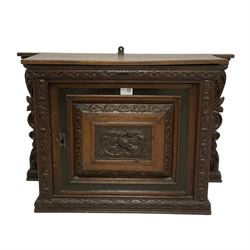 18th century carved oak cupboard, enclosed by panelled door carved with central bird motif and scrolled leafage with an outer ebony band, the frieze and uprights carved with repeating lunette and floral designs, flanked by scrolled foliate carved upright brackets