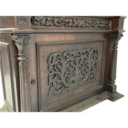 19th century oak gun cabinet, projecting leaf carved and moulded cornice, stepped shouldered arch glazed door flanked by two spiral turned pilasters, drawer with applied scrolling foliage carving over panelled cupboard, the door set with carved interlace foliate mount, moulded base