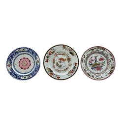 Three 18th century Chinese porcelain Famille Rose plates, the first painted with a central pair of Buddhist lion dogs playing with ribbons and brocade balls D25cm, the second centrally painted with a lotus flower within a blue border and the third painted with exotic birds within a foliate border (3)