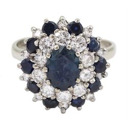 White gold sapphire and diamond cluster ring, the central oval cut sapphire, with round cut sapphire and round brilliant cut diamond surround, stamped 18ct, 