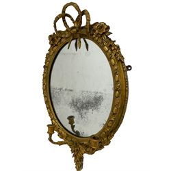 19th century gilt wood and gesso Girandole mirror, oval frame with ribbon tied pediment and extending floral decoration, the frame with foliate and egg and dart moulding, two branch candle holder over trailing laurel leaves and flower heads