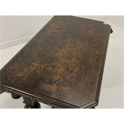 Victorian Gothic revival oak centre table, rectangular top with canted corners embellished with lion masks, cushion frieze, raised on four turned columns leading to sledge supports carved with fish, 107cm x 67cm, H76cm