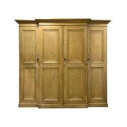 Late 19th century scumbled pine breakfront triple wardrobe or housekeepers cupboard, projecting ovolo cornice, central panelled doors with moulded edges enclosing main cupboard, the left cupboard fitted with upper shelf over hanging rail, the right fitted with four shelves with single drawer to base