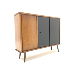 Mid 20th century teak and oak sideboard or bookcase, fitted with three sliding doors enclosing adjustable shelves, raised on turned supports, W109cm, H84cm, D27cm