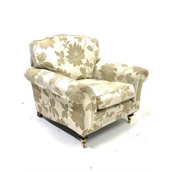 Contemporary armchair, upholstered in cream floral fabric with loose cushions, raised on square tapered supports with brass cup castors W96cm