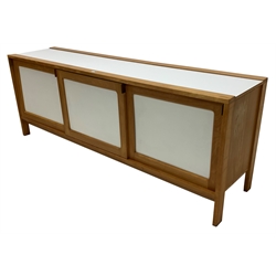 Mid to late 20th century beech and white laminate sideboard, three sliding doors enclosing shelves and drawers, raised on square supports 