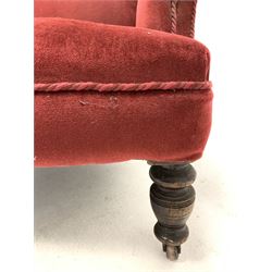 Edwardian wingback armchair, upholstered in red fabric, raised on turned front supports with castors 