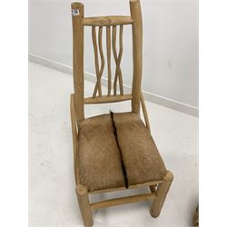 Occasional chair of primitive design, with spindle back, seat covered in possibly dear hide, raised on unfinished circular section supports, (W46cm) together with a glass topped table of a similar design (D50cm H51cm)
