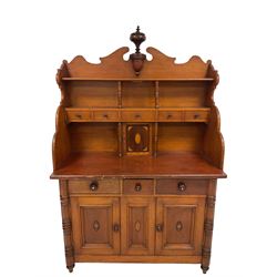 Late 19th century pine and mahogany bespoke dresser, broken swan pediment with central turned baluster finial, the top section fitted with plate rack supported by ring turned columns, central shelf fitted with five drawers over central panelled cupboard door inlaid with satinwood scalloped decoration, all flanked by swept and shaped uprights, the lower section fitted with three drawers over two panelled cupboards with moulded edges, each with turned wood handles and inlaid with urns, central panel inlaid with conch shell, the turned uprights terminating in tulip feet