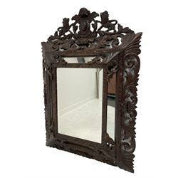 Large Victorian cushion framed wall mirror, the carved and pierced pediment with central cartouche flanked by two standing lions and foliate c-scrolls, the frame carved with scrolling foliage and incised decoration, the main bevelled mirror plate surrounded by plain plates, mounted by scrolled foliage corner brackets