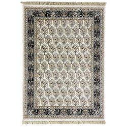 Persian design densely knotted ivory ground carpet, the field decorated with repeating motifs depicting floral urns, guarded indigo ground border with trailing foliate and flower head decoration